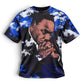 A short-sleeve crewneck t-shirt featuring a graphic print of Martin Luther King Jr. on the front, set against a blue and white digital camouflage pattern on the sleeves and sides, displayed on a clean white background.